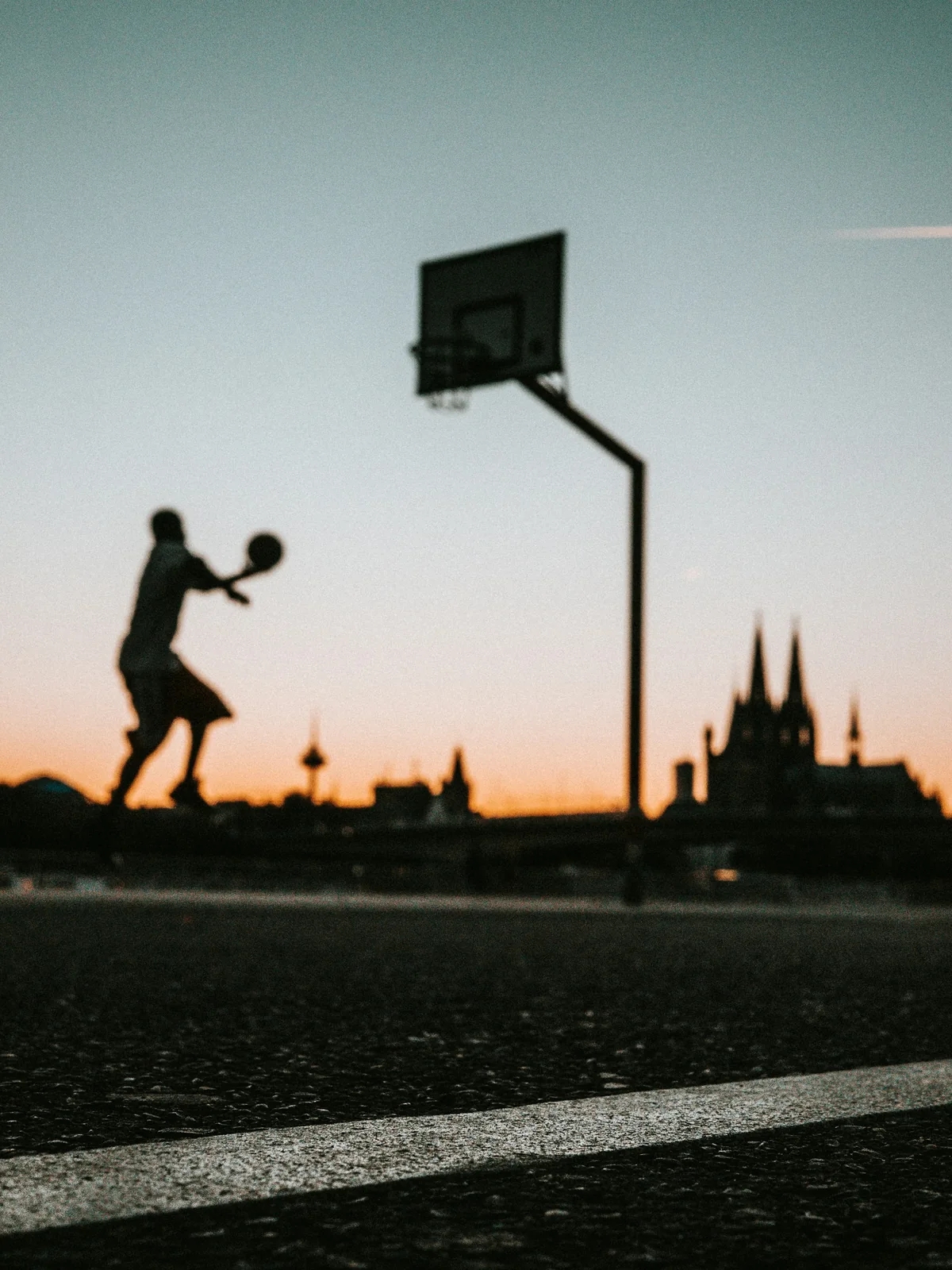 A basketball player rising toward the hoop at sunset